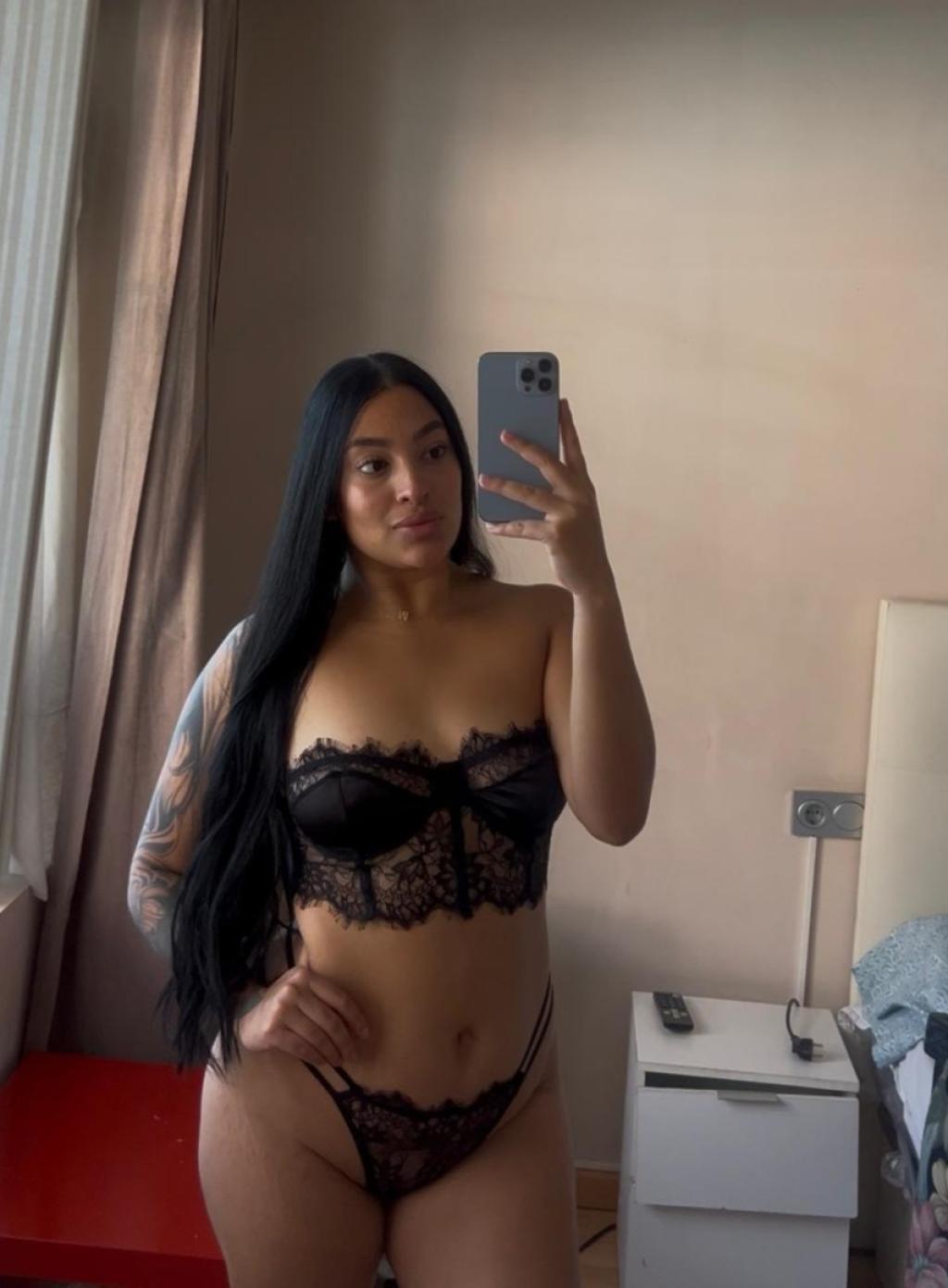 Escort en Pamplona con cabello largo y lacio, vistiendo lencería negra de encaje en un entorno interior.