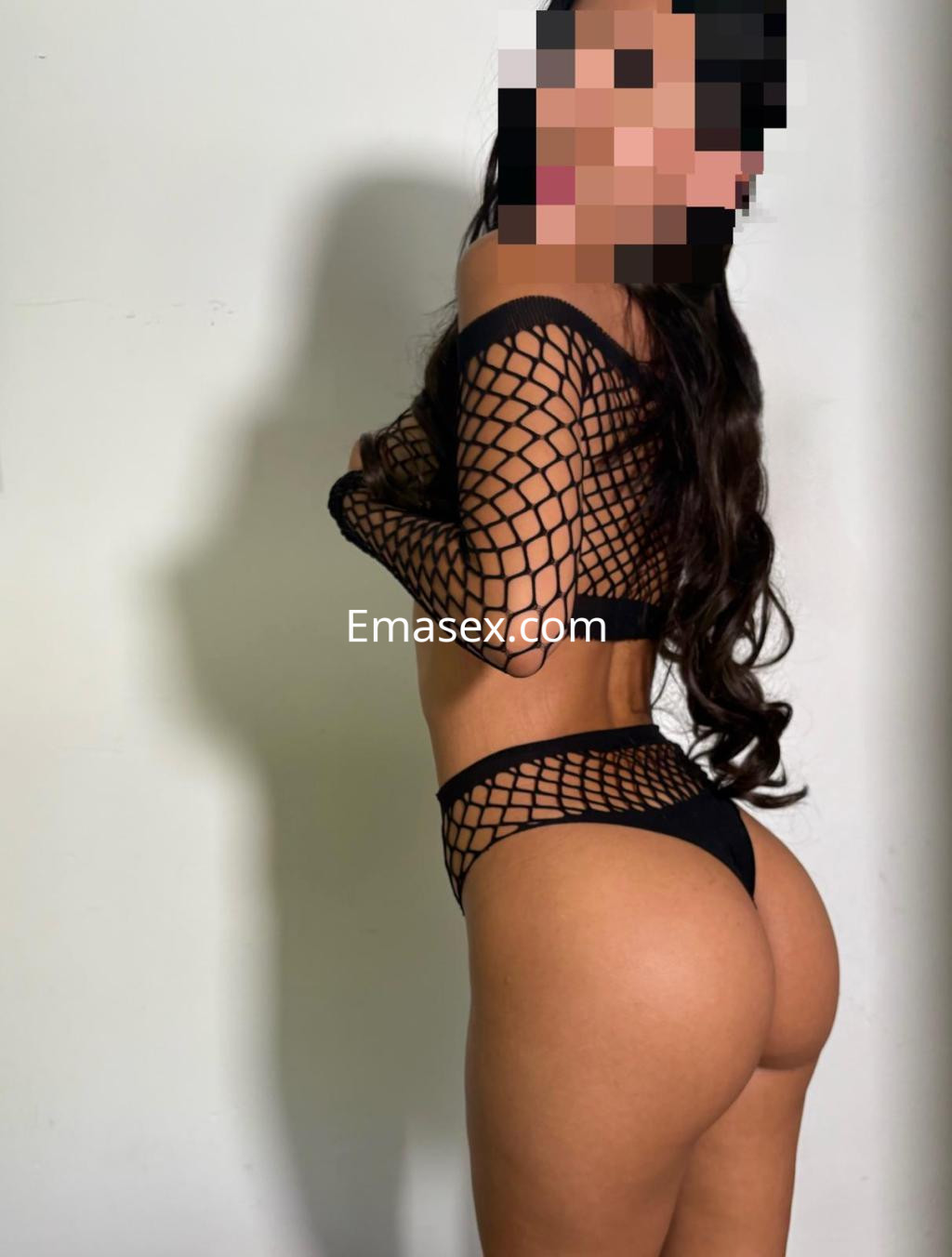 Escort en Toledo, vistiendo una malla negra de red que realza su figura, posando de perfil.