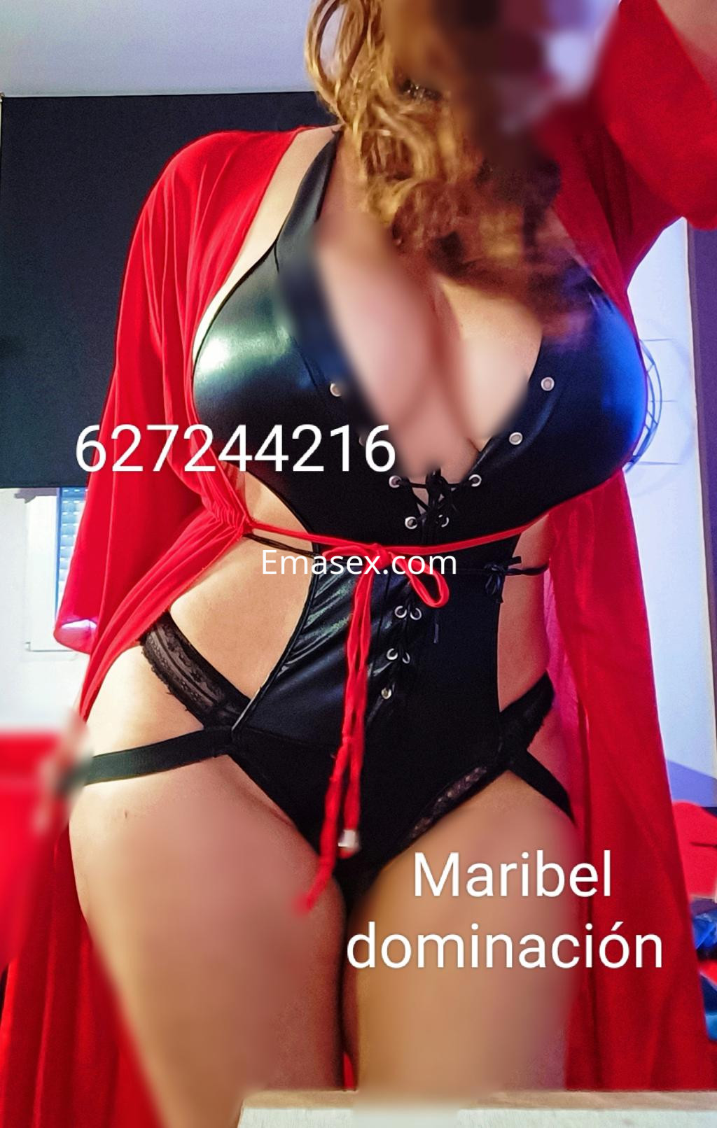Puta en Santiago viste un conjunto de lencería negra con detalles de encaje y un abrigo rojo, posando con confianza.