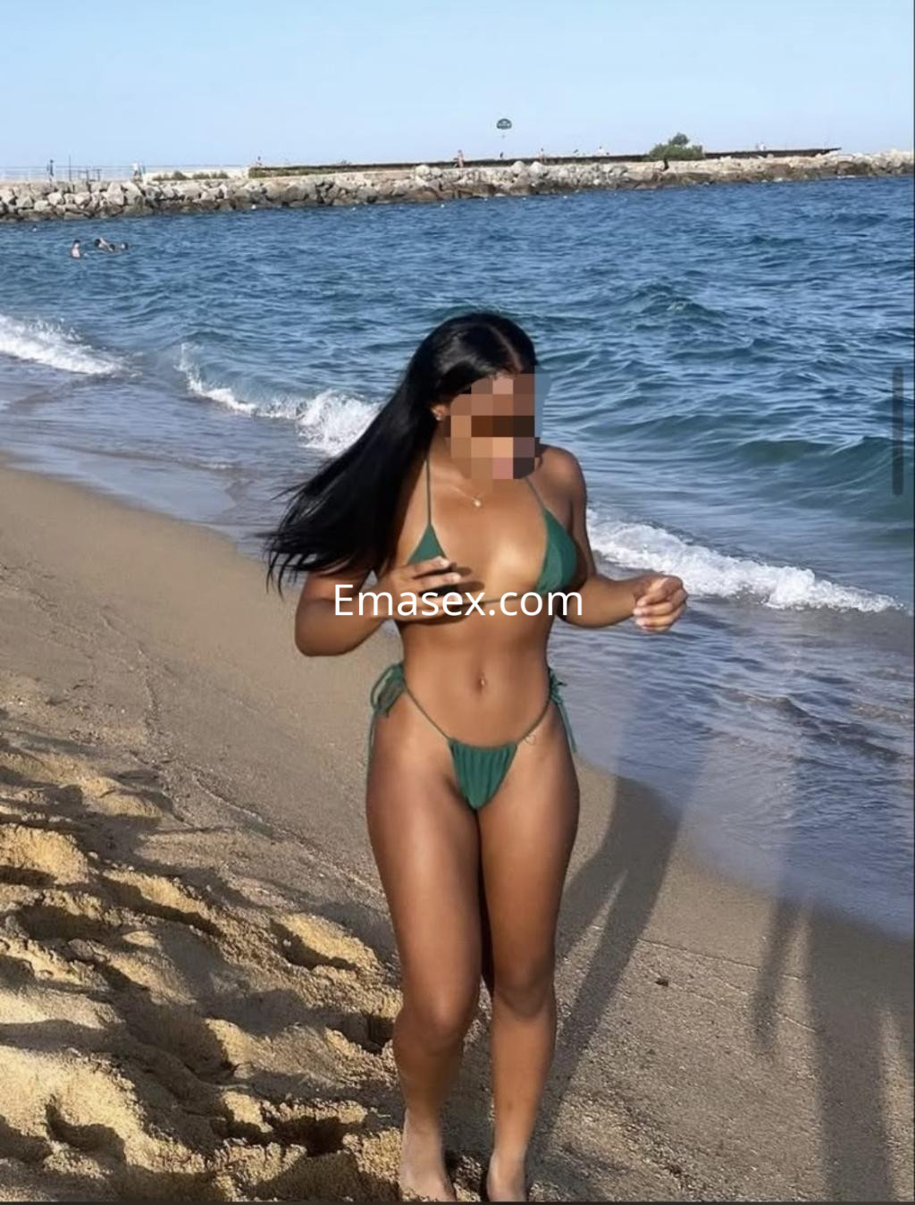 La puta camina por la playa de Toledo, luciendo un bikini verde y mostrando su figura bronceada.