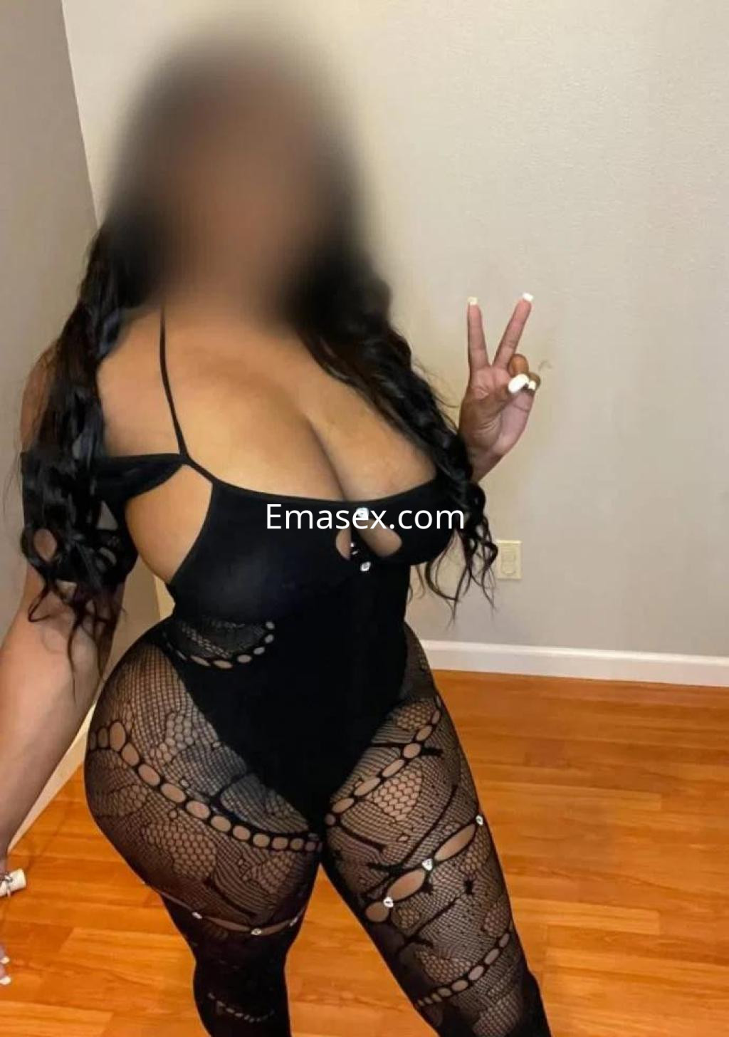 Escort en Cáceres viste un body negro ajustado con detalles de encaje, mostrando una pose de paz.