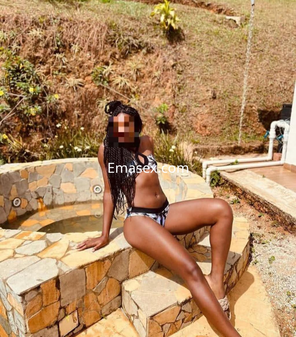Escort en Coruña sentada al borde de una jacuzzi, luciendo un bikini negro y blanco, con cabello trenzado.
