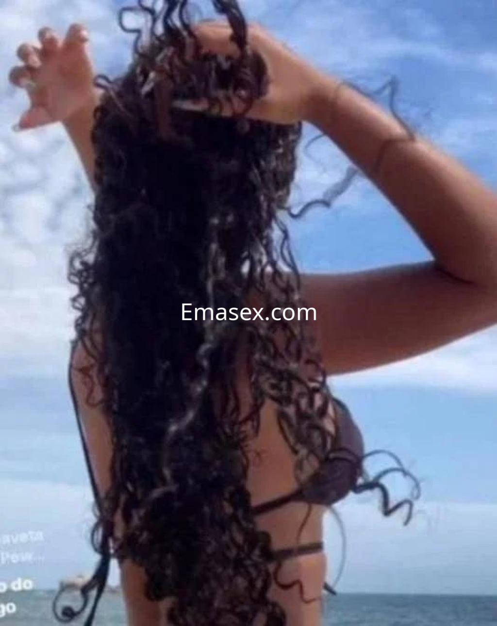 Puta de cabello rizado y largo, con bikini negro, disfrutando de un día soleado en la playa de Cáceres.