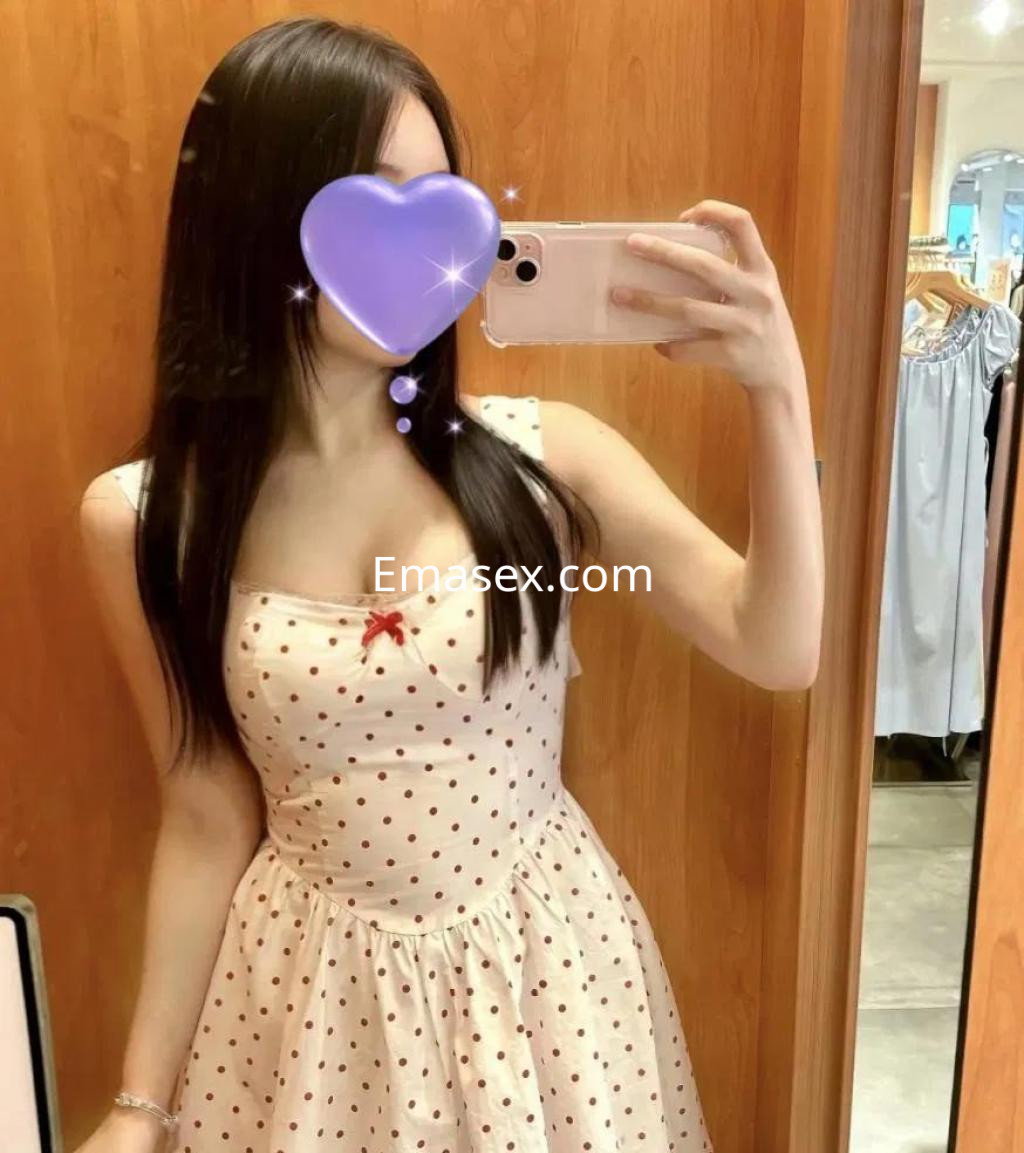 Puta con cabello largo y lacio, vestida con un vestido de tirantes blanco con lunares rojos, en un espejo en Madrid.