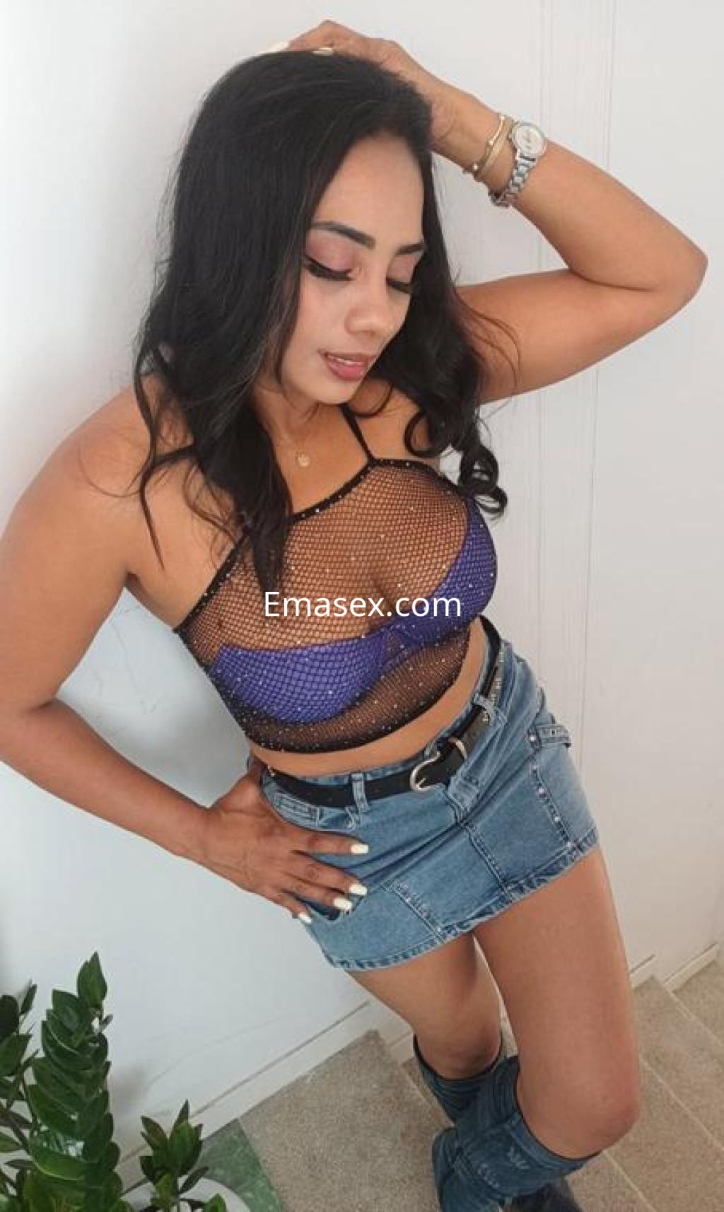 Escort en Barcelona con blusa de malla negra y azul, falda de mezclilla, peinada con cabello oscuro y suelto.