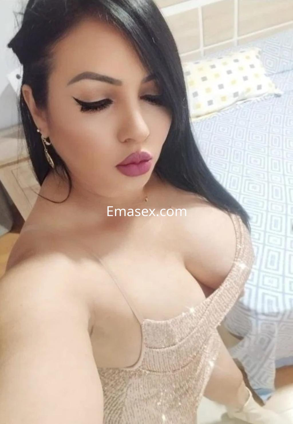 Escort en Zamora con cabello largo y lacio, luciendo un vestido brillante y ajustado en un entorno interior.
