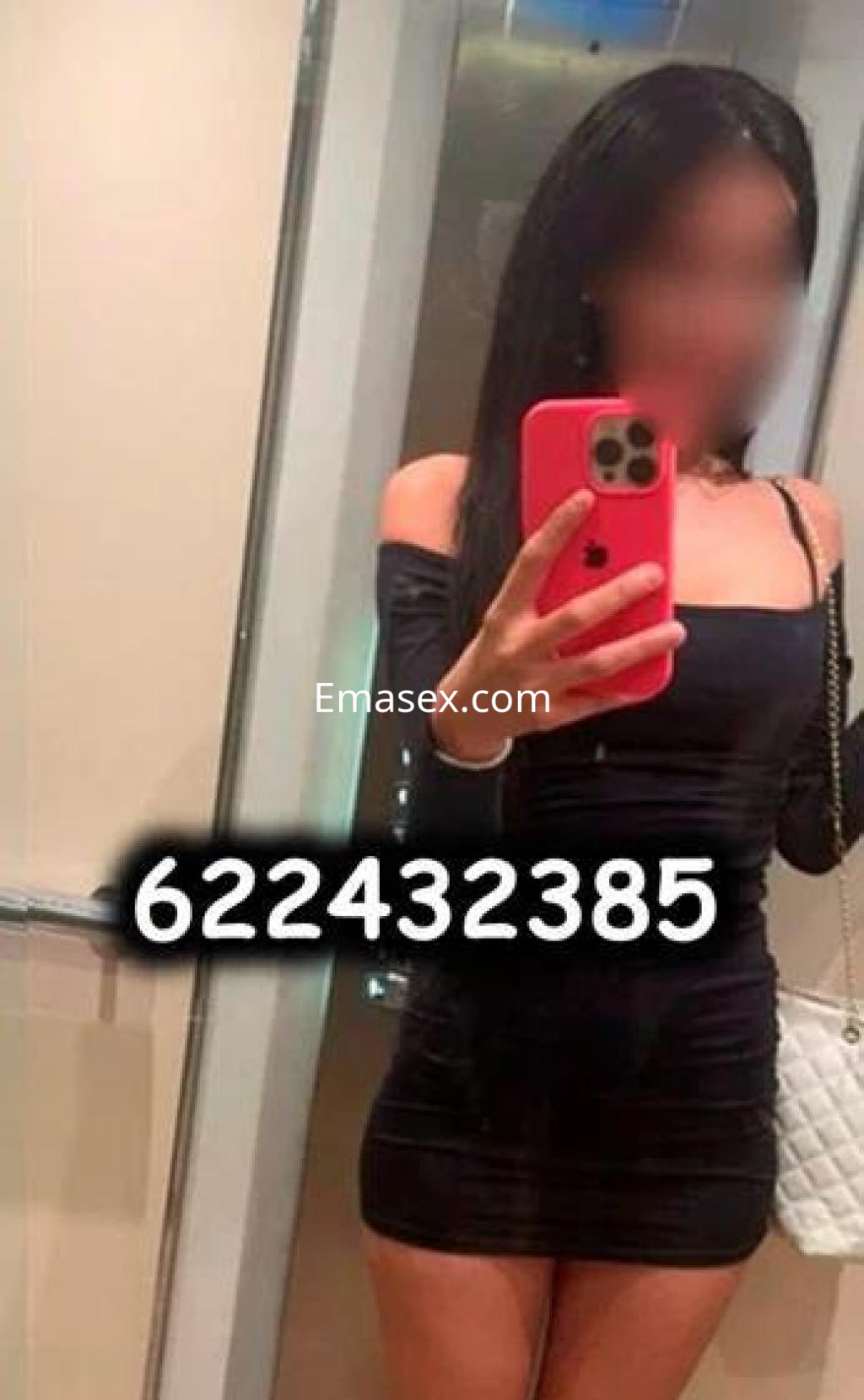 Puta en Badajoz luce un vestido negro ajustado, con tirantes, mientras toma una selfie en un espejo.
