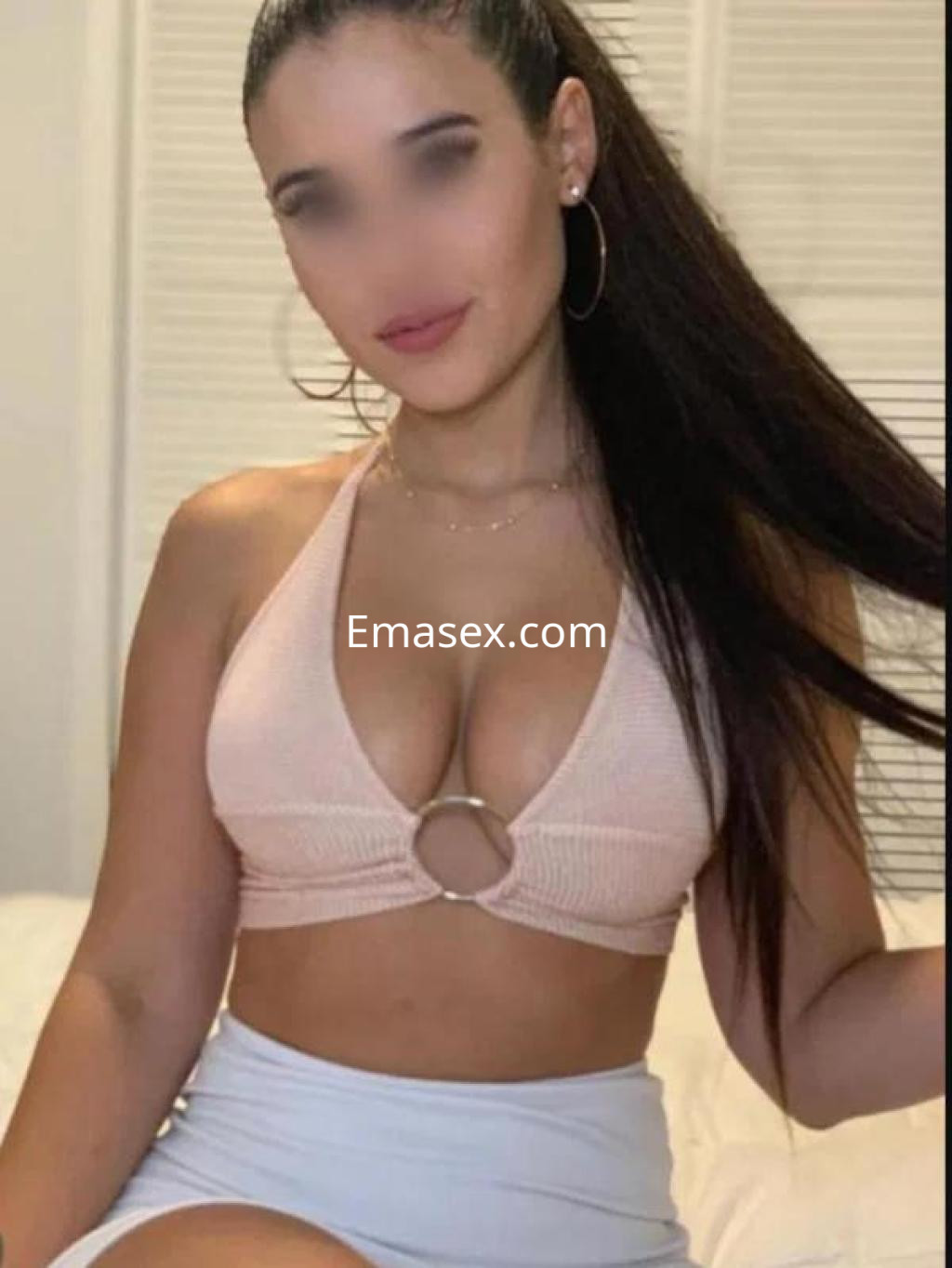 Escort en Badajoz luce un top rosa con anillo en el centro y una falda corta, mostrando una pose confiada.