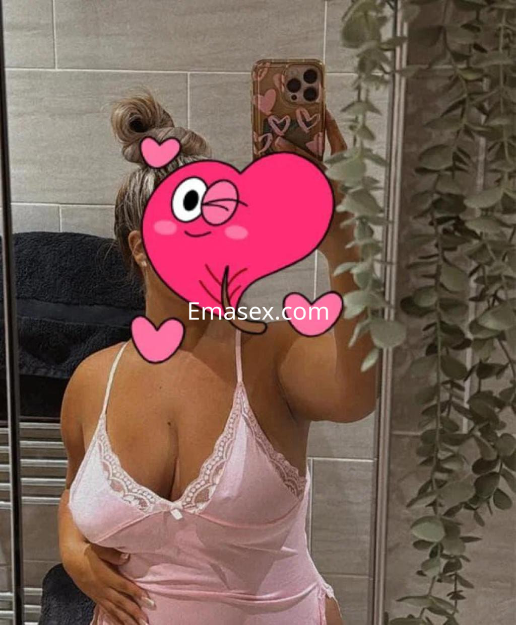 Puta con cabello rubio recogido, viste un conjunto rosa que resalta su figura en un baño de Castellón.