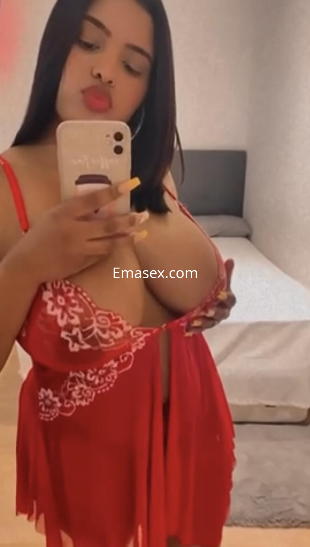 La puta se muestra en un vestido rojo con detalles florales, posando frente a un espejo en Bilbao.