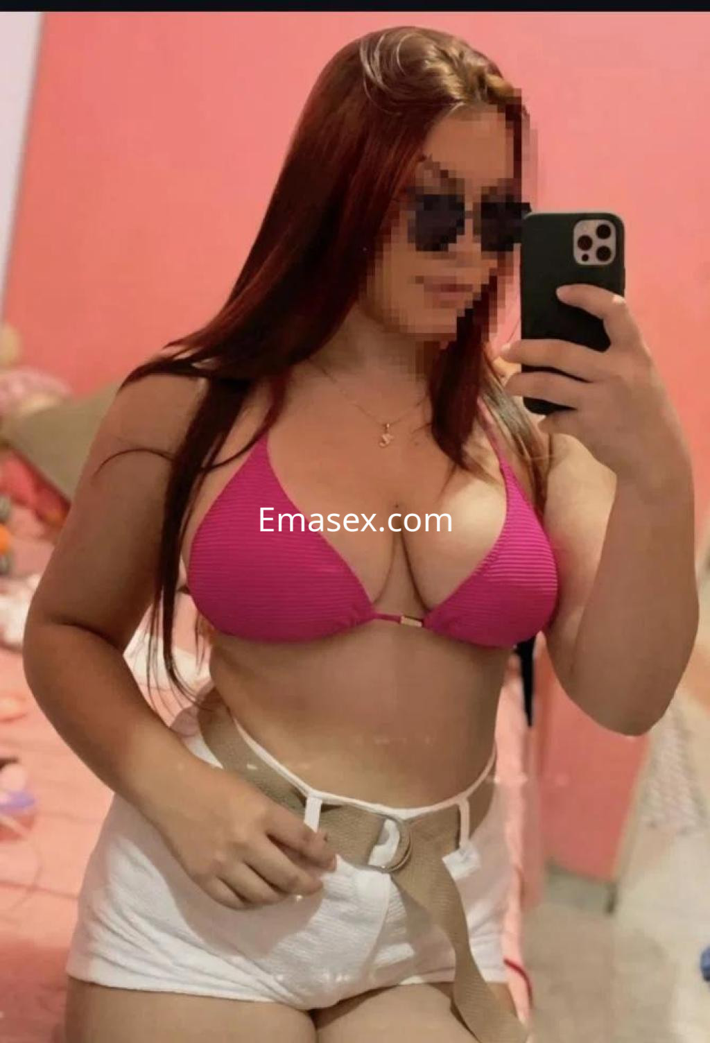 Puta en Cáceres posa con un bikini rosa y pantalones cortos, luciendo gafas de sol y cabello largo.
