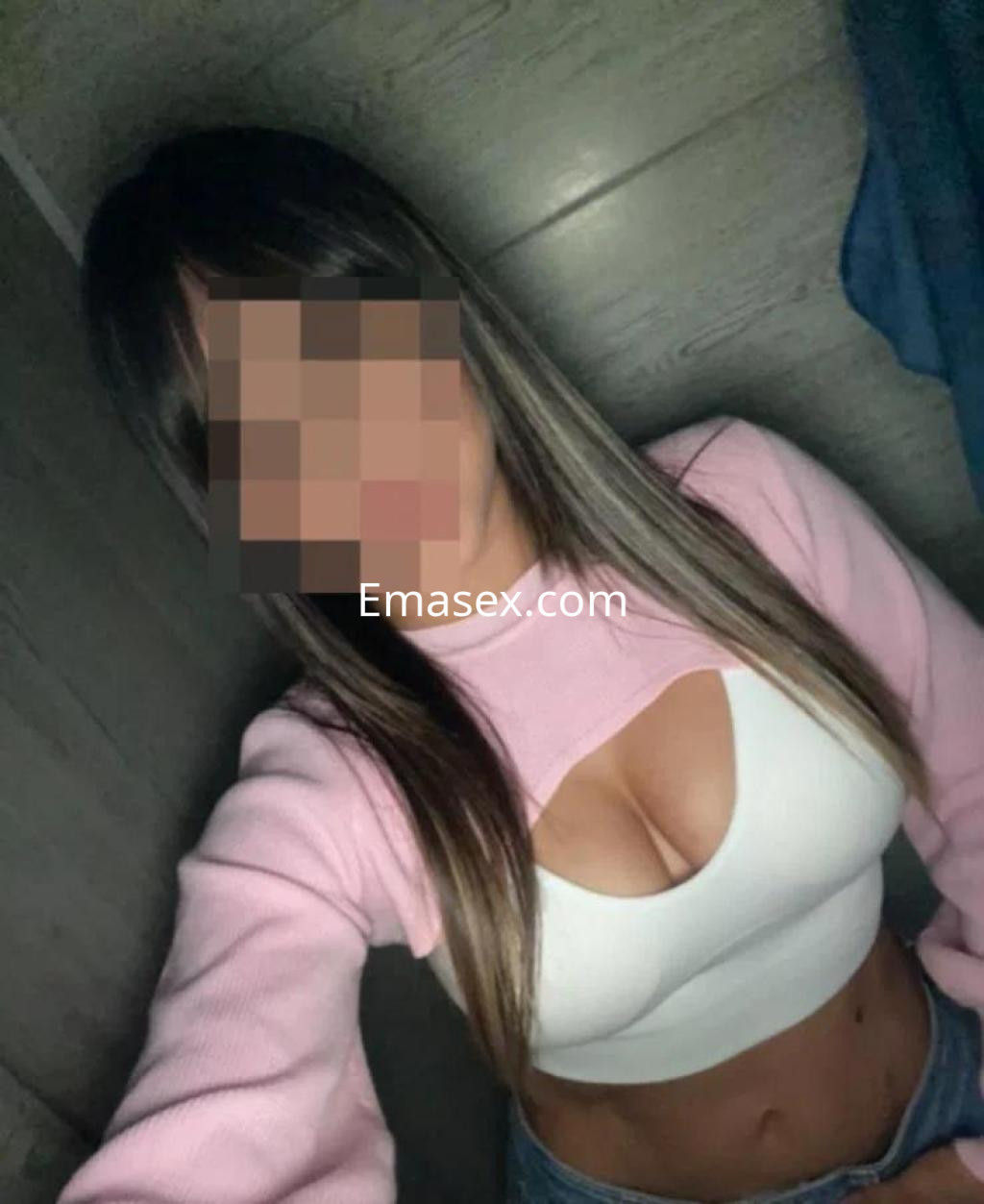 Escort en Toledo con cabello largo y lacio, vistiendo un suéter rosa y top blanco que resalta su figura.