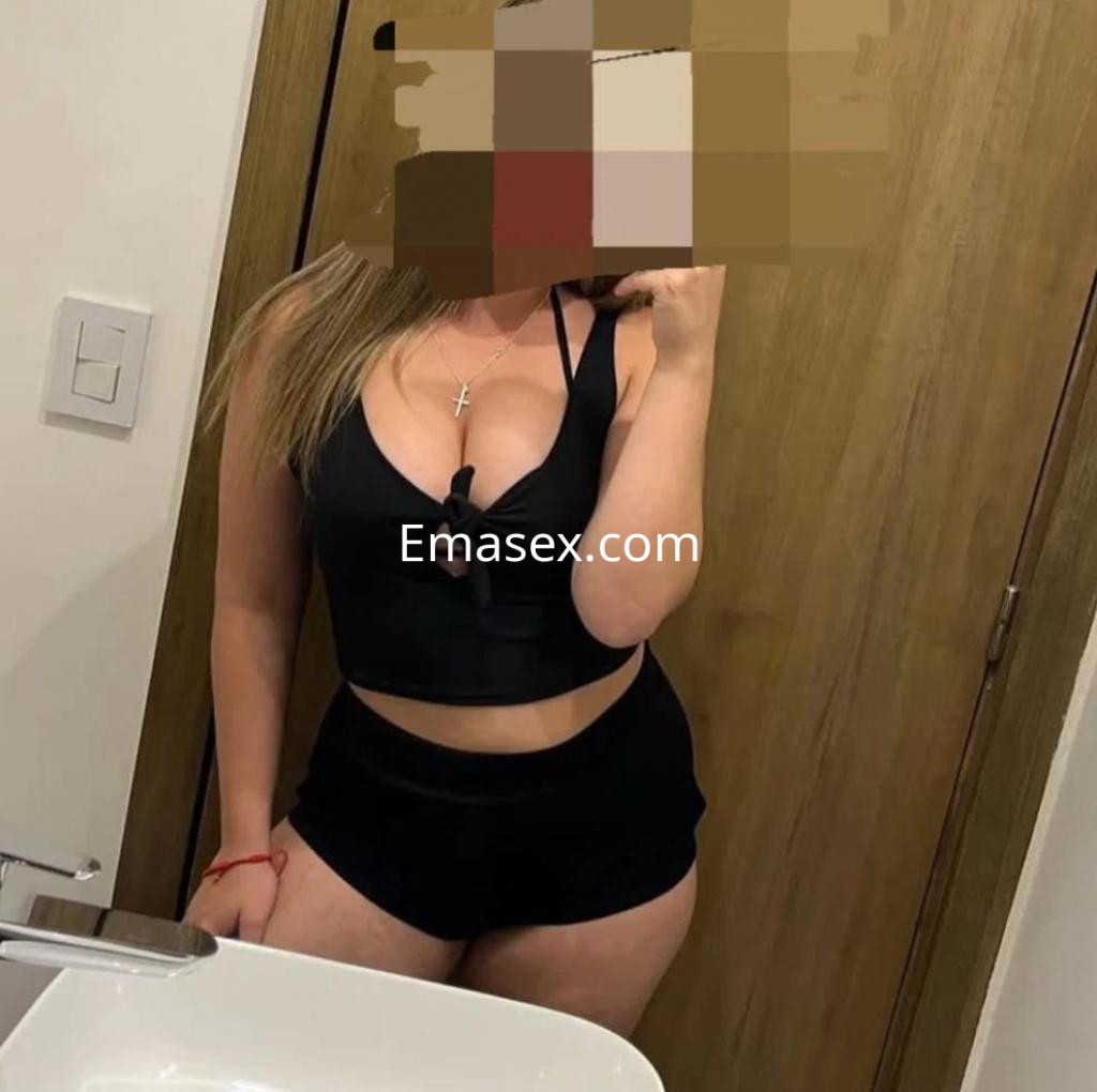 Puta posando en un baño con top negro y pantalones cortos, mostrando una actitud seductora en Albacete.