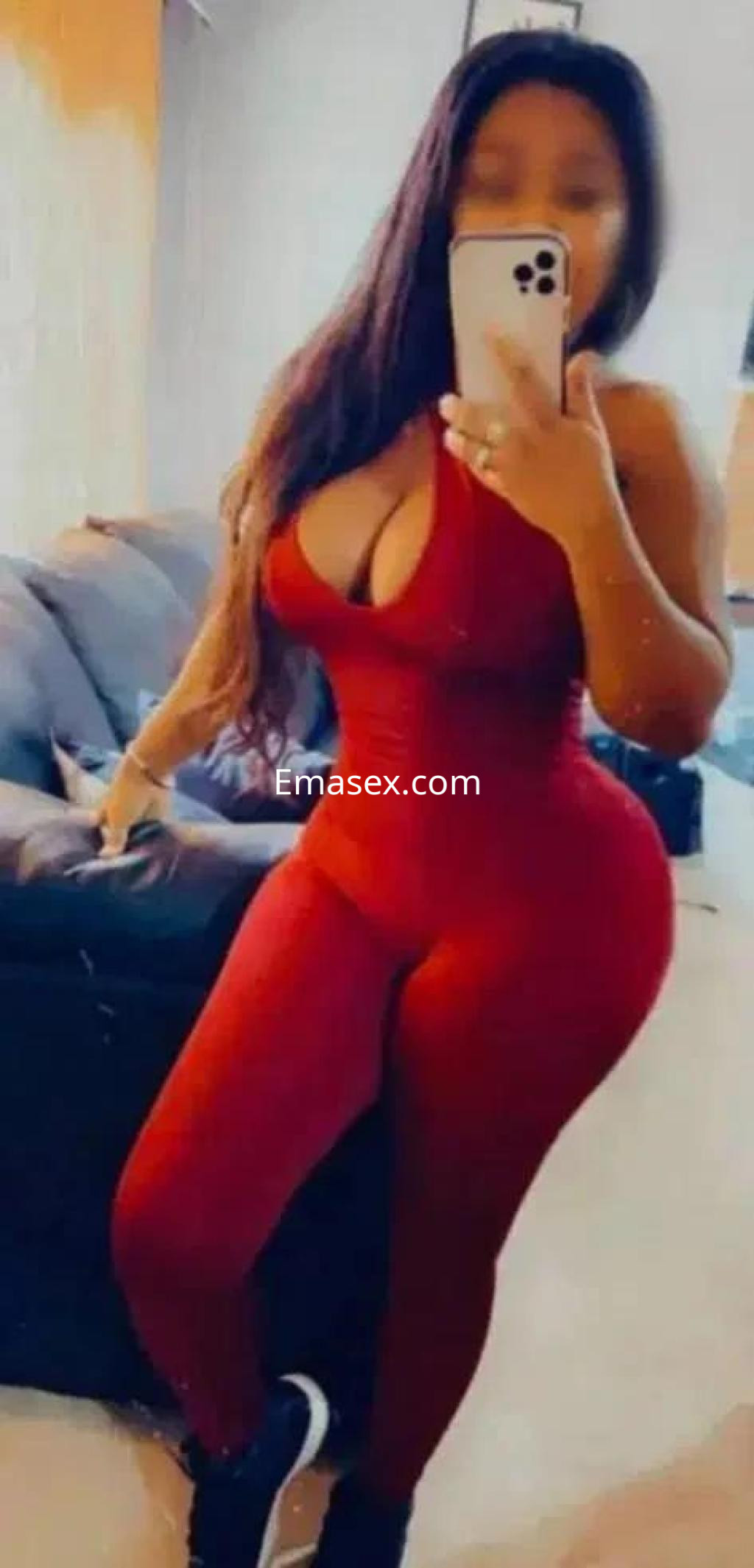 Escort en Córdoba posando con un ajustado overol rojo que resalta su figura, con cabello largo y ondulado.