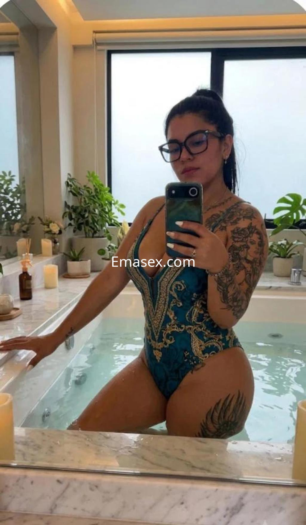 La puta se muestra en un bañador azul con detalles dorados, posando frente a un espejo en Málaga.