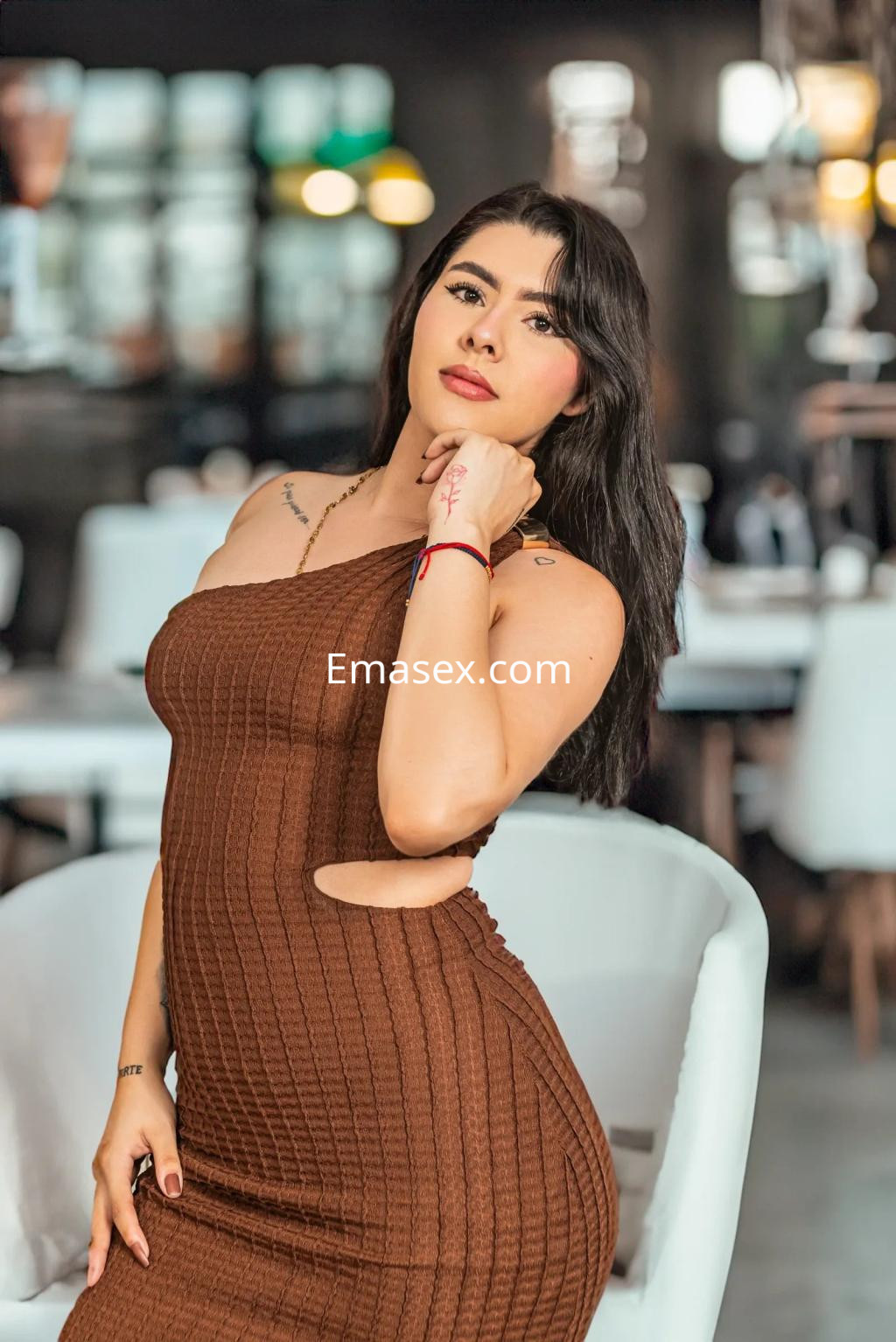 Escort en Alicante con vestido ajustado de color marrón, posando en un ambiente moderno y elegante.
