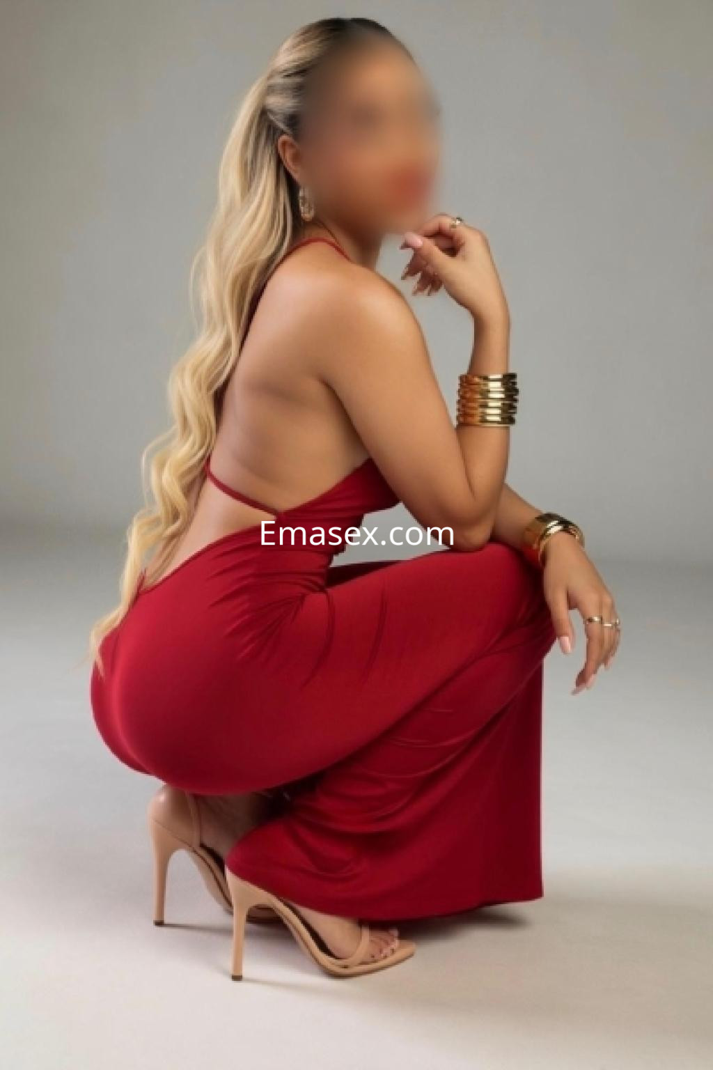 Puta con cabello largo y rubio, viste un vestido rojo ajustado y tacones, posando de perfil en Almería.