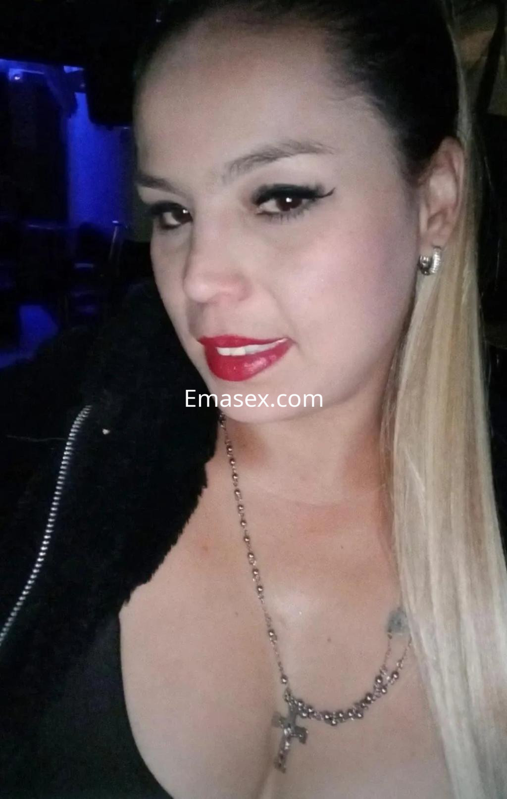 Puta con cabello rubio largo y lacio, labios rojos y mirada seductora, posando en un ambiente nocturno en Burgos.