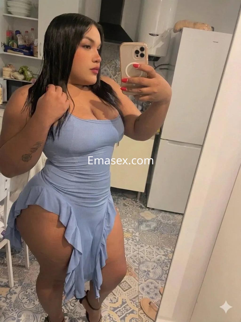 Escort en Cádiz, con cabello oscuro y lacio, viste un vestido azul claro ajustado que resalta su figura.