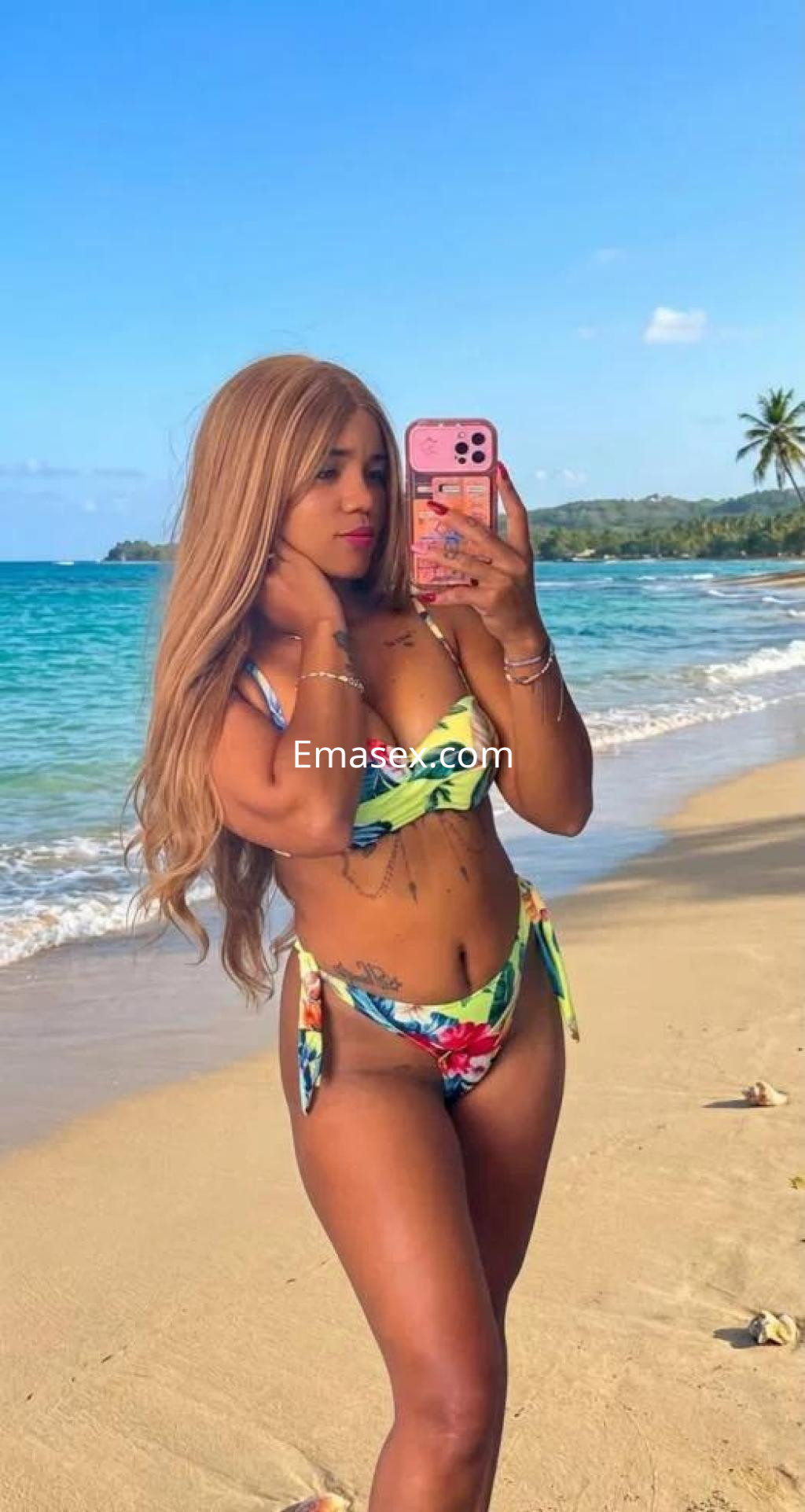 Puta posando en la playa de Málaga, luciendo un bikini colorido y cabello largo y lacio, con el mar de fondo.