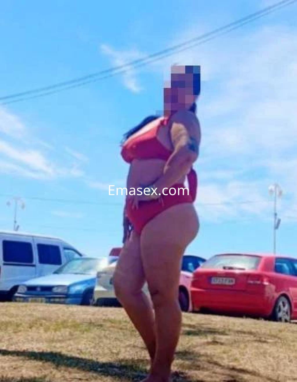 Puta posando en un bikini rojo en un día soleado en Pontevedra, con un fondo de coches y césped.