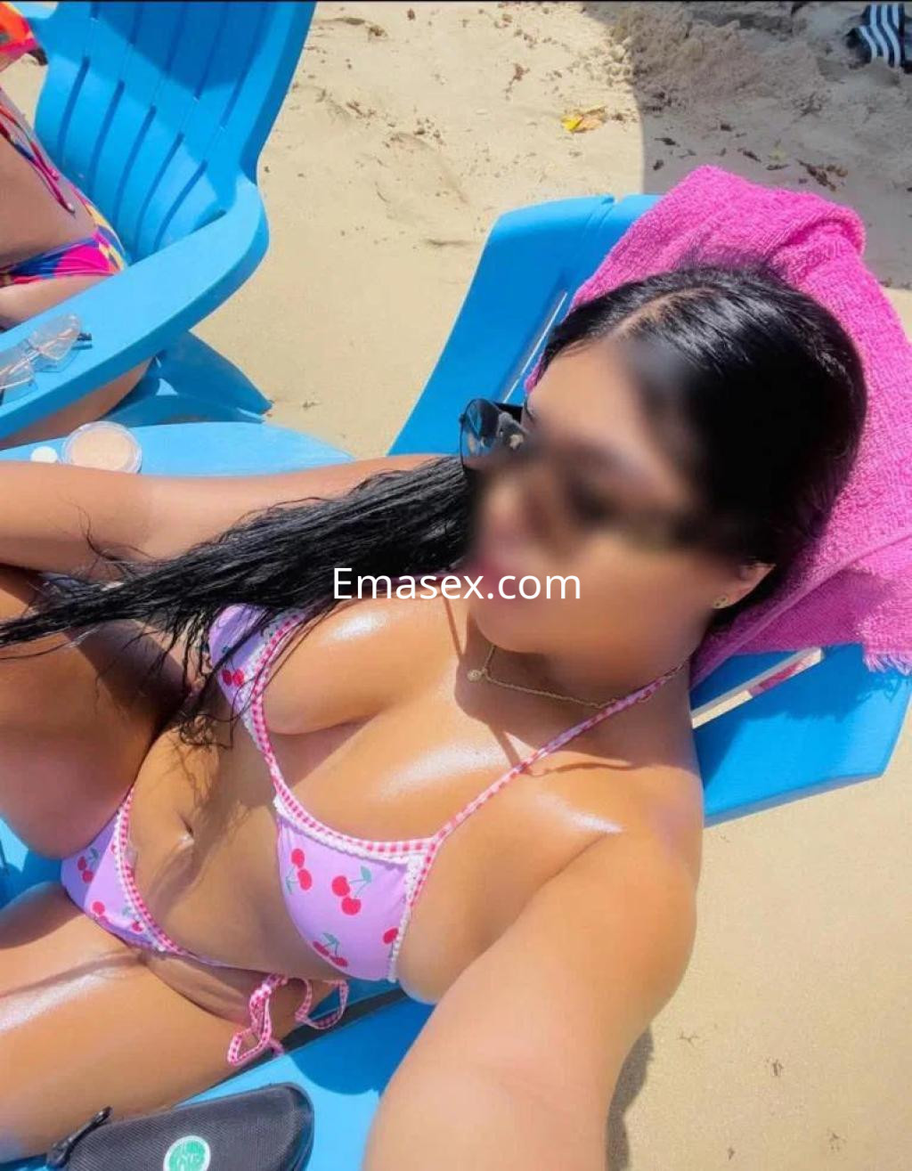 La puta luce un bikini rosa con estampado de cerezas, disfrutando del sol en la playa de Bilbao.