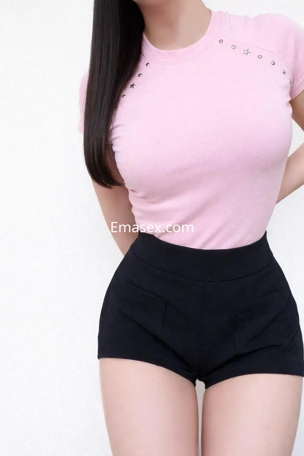Puta en Valencia luce una camiseta rosa ajustada y pantalones cortos negros, mostrando una pose coqueta.