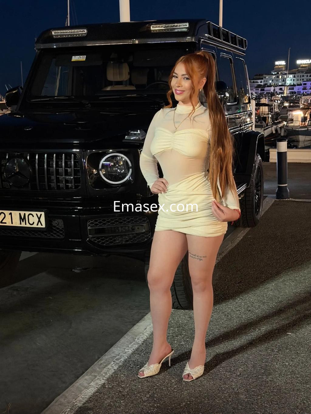 Puta posando con un vestido ajustado y transparente, junto a un coche negro en Zaragoza de noche.