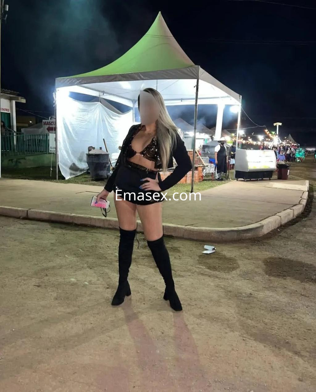 Escort en Albacete con cabello largo y rubio, luciendo un atuendo de lencería y botas altas en un evento nocturno.