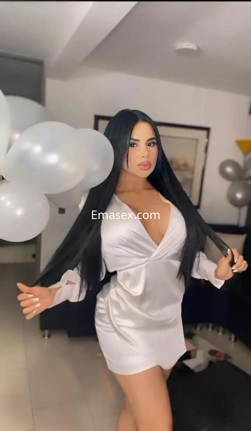 Puta en Palma de Mallorca con vestido satinado, cabello largo y lacio, posando en un ambiente festivo.