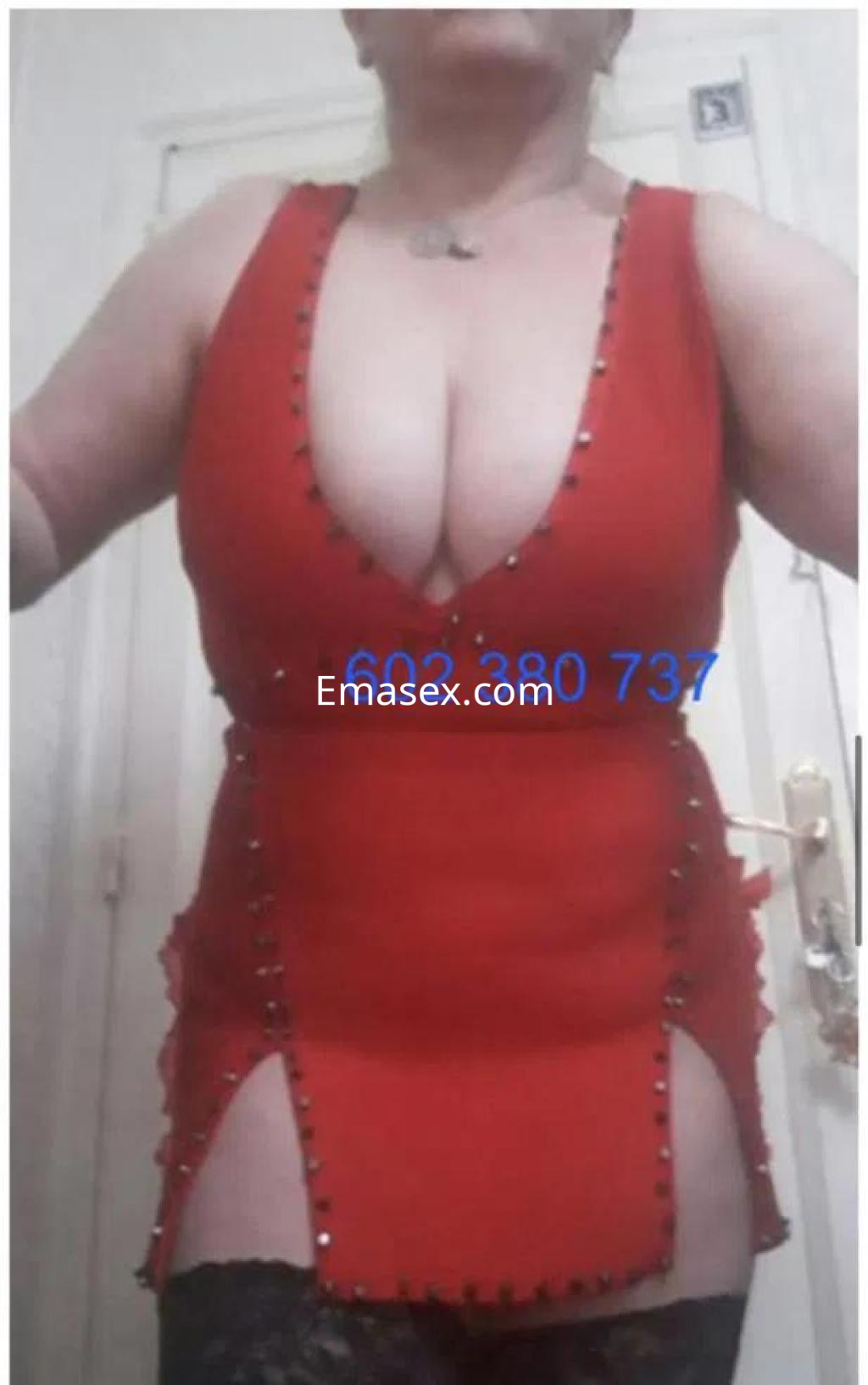 Puta en Barcelona vistiendo un vestido rojo ajustado con escote profundo y detalles brillantes, mostrando su figura.