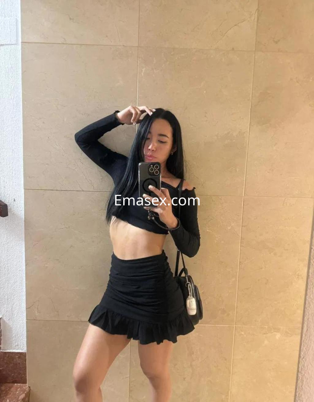 Escort en Castellón luciendo un top negro de manga larga y una falda corta, con cabello lacio y oscuro.