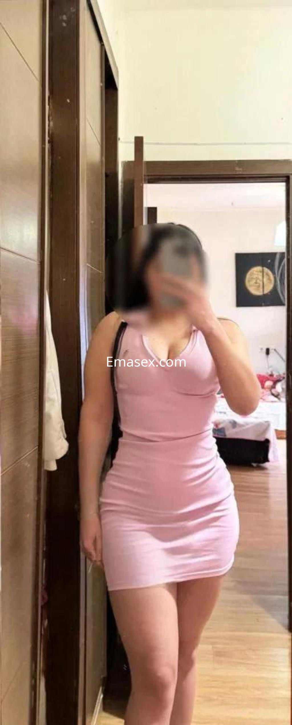 La puta viste un ajustado vestido rosa que resalta su figura en un ambiente interior de Granada.