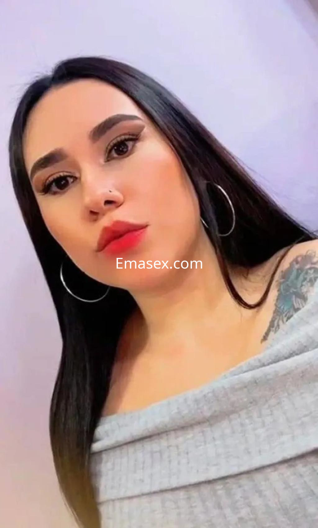 Escort en Oviedo con cabello largo y lacio, luciendo un top gris y aretes grandes, con un maquillaje destacado.