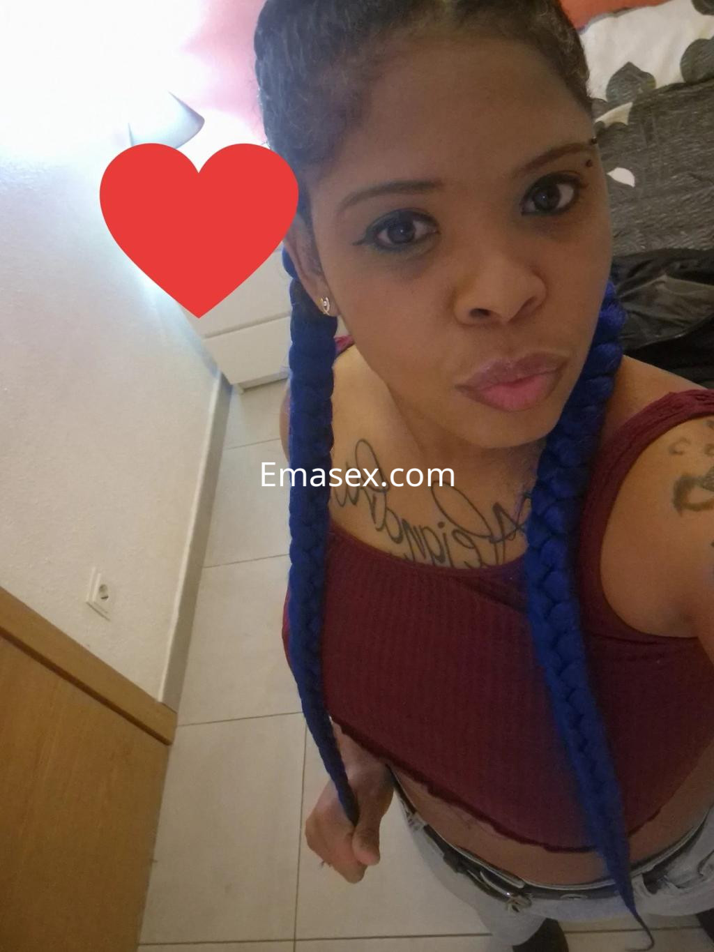 Puta en Oviedo con cabello largo y trenzado de color azul, luciendo una blusa ajustada y jeans.