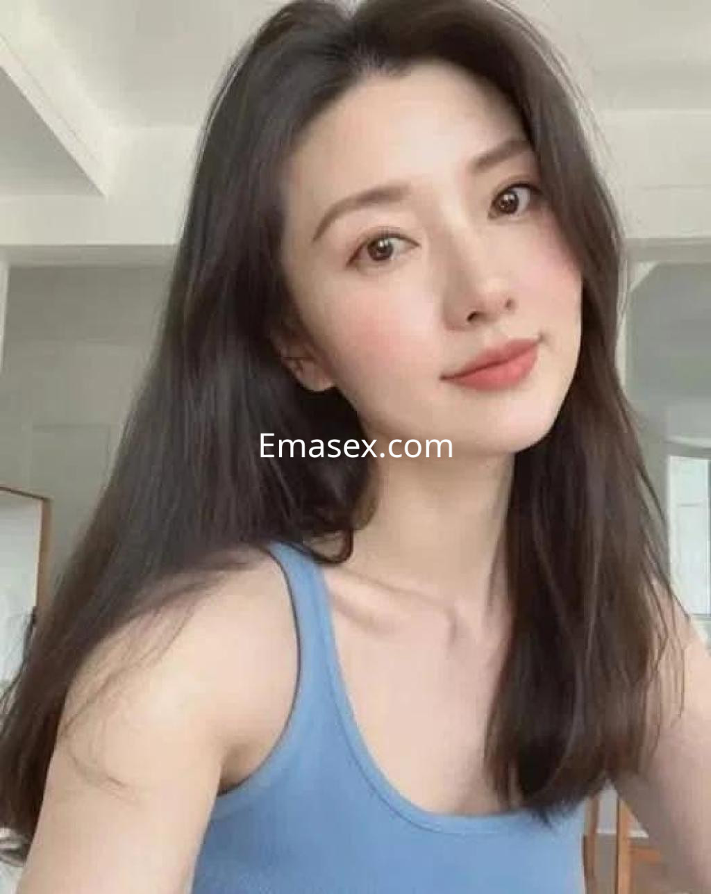 Escort en Salamanca con cabello largo y lacio, viste una blusa azul y sonríe en un entorno luminoso.