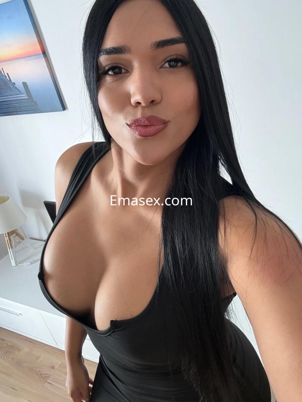 Puta en Zaragoza con vestido negro ajustado y cabello largo, posando con una expresión coqueta.