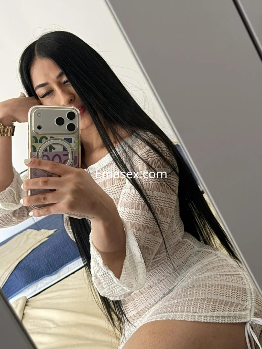 Escort en Barcelona, con cabello largo y lacio, viste un vestido blanco y se toma una selfie en un espejo.