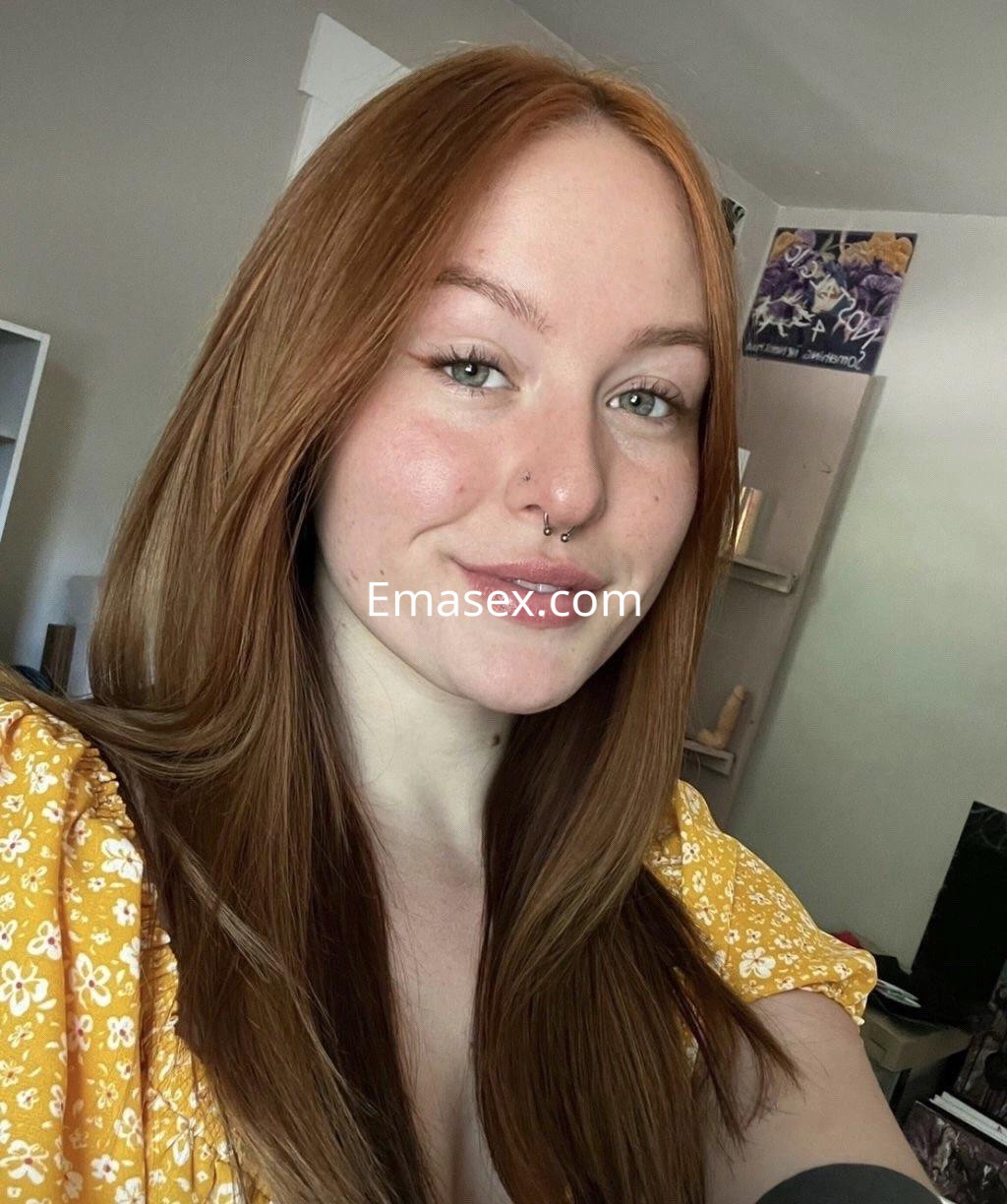 La puta de Málaga muestra su cabello largo y pelirrojo, con una blusa amarilla y una sonrisa alegre.