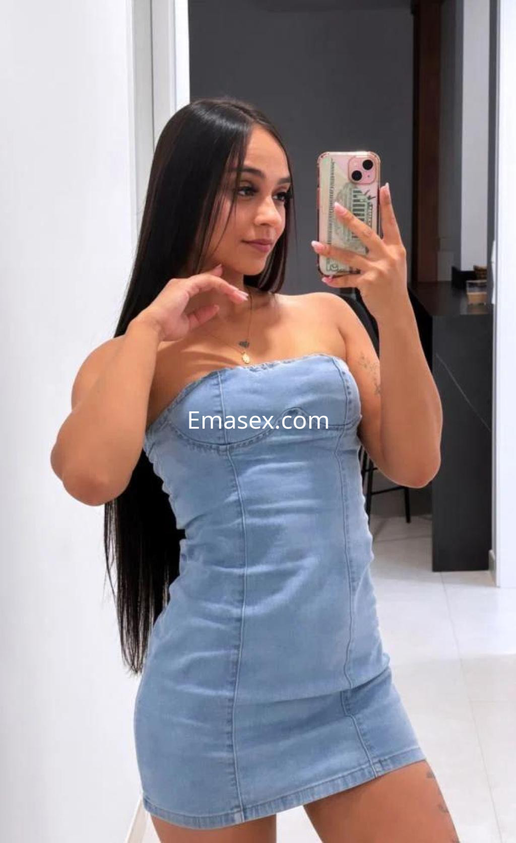 La escort en Alicante posa con un vestido de mezclilla ajustado, mostrando su cabello largo y lacio.