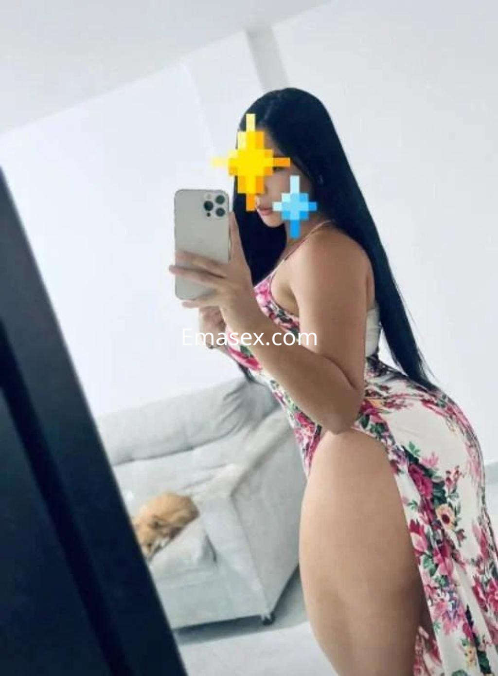 Puta en Murcia posando con un vestido floral ajustado que resalta su figura, en un entorno moderno.