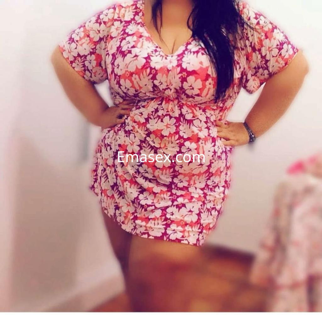Puta en Vigo luce un vestido floral ajustado, con un escote pronunciado y posando con confianza.