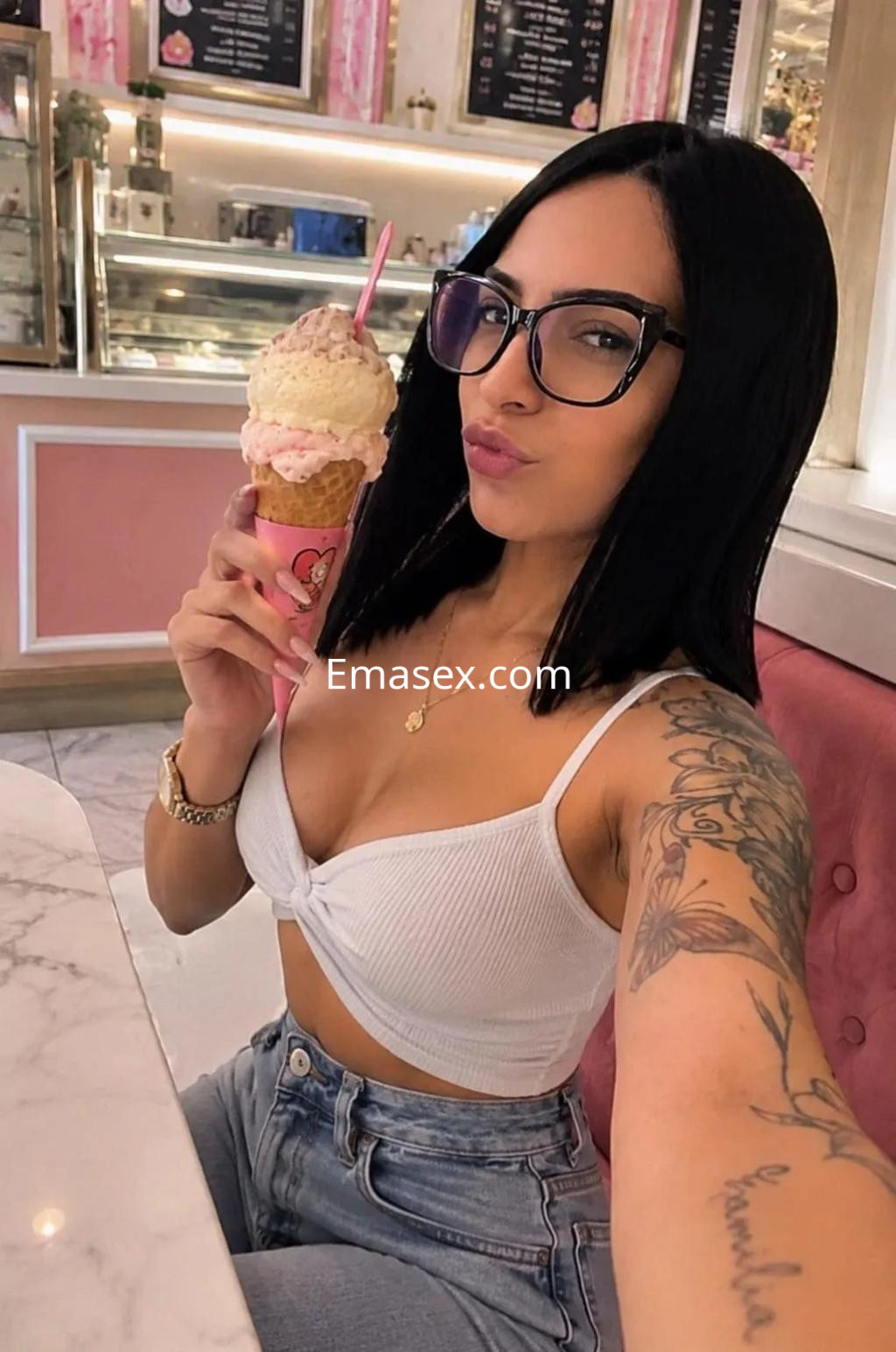 Escort en Zaragoza posando con un helado, viste un top blanco y jeans, con cabello largo y lacio.