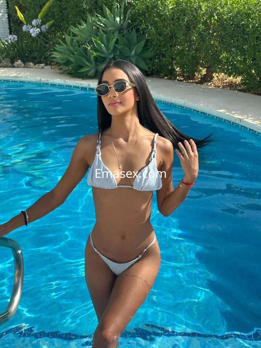 Escort en Zaragoza con cabello largo y lacio, luciendo un bikini blanco junto a una piscina, disfrutando del sol.