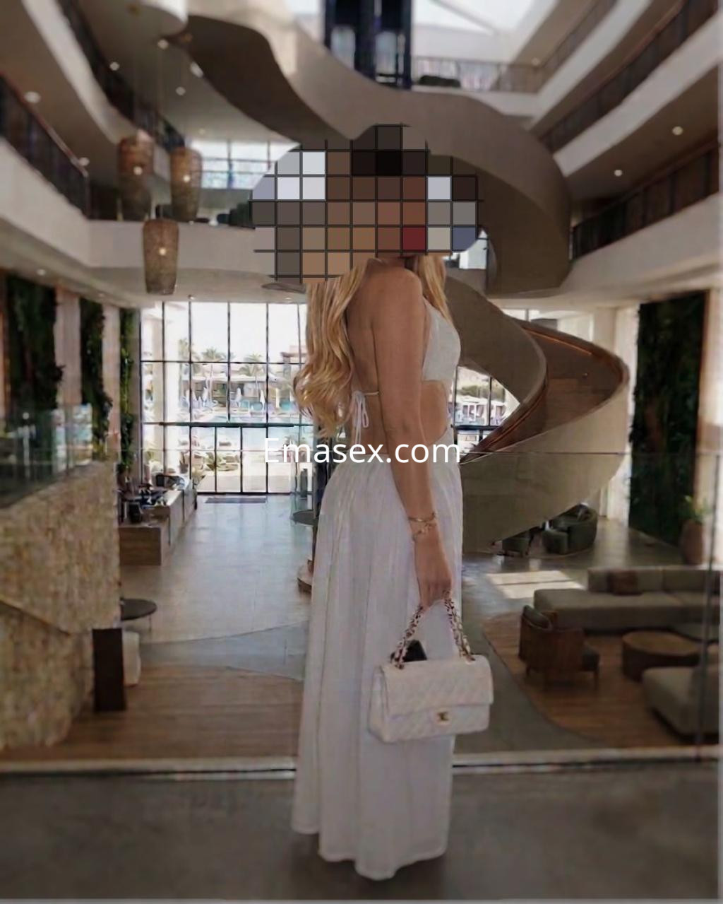 Puta de cabello largo y rubio viste un vestido blanco, posando elegantemente en un lujoso espacio en Tenerife.