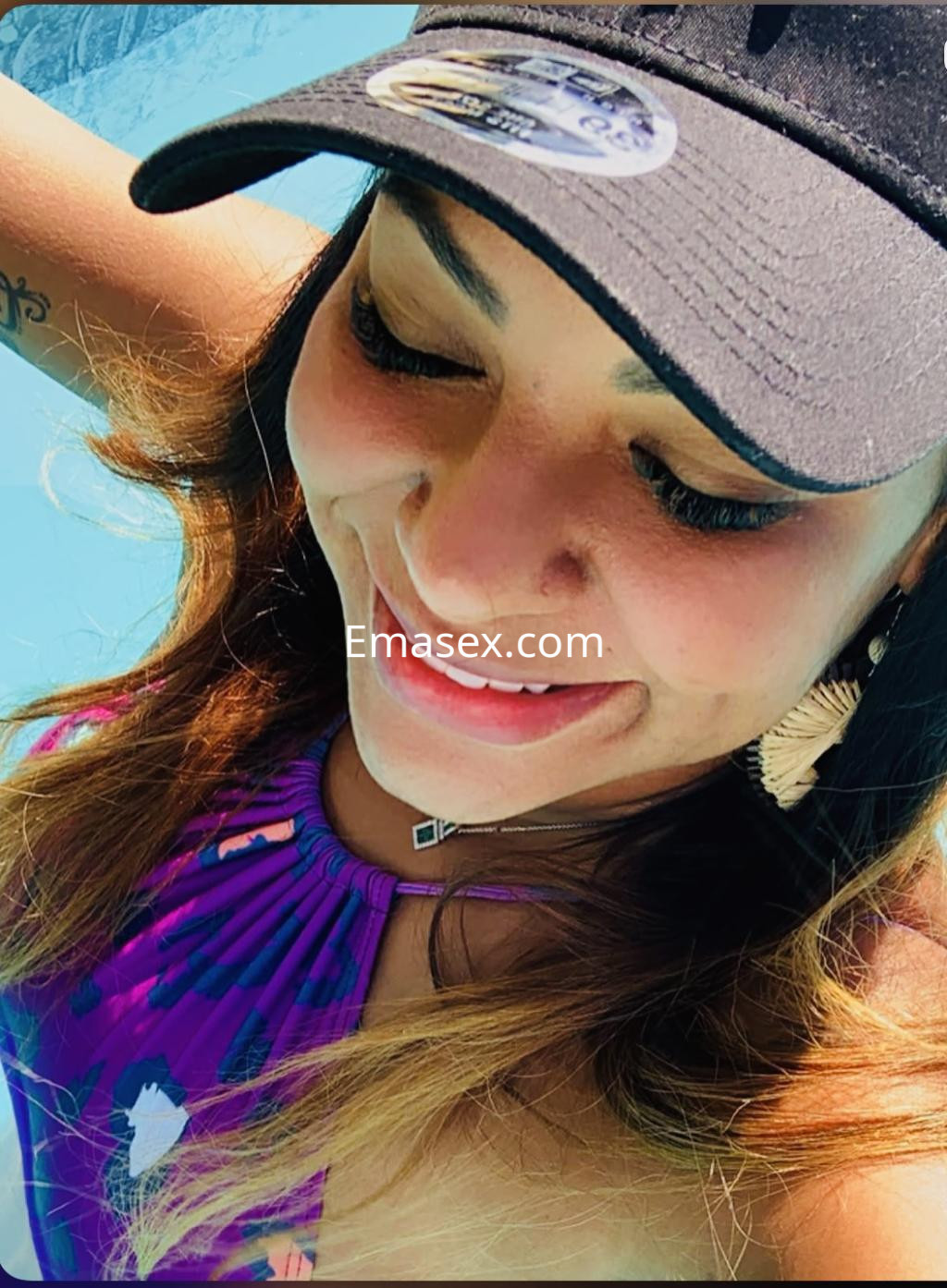 Puta en Pamplona con un bañador colorido y gorra negra, sonriendo mientras se sumerge en la piscina.