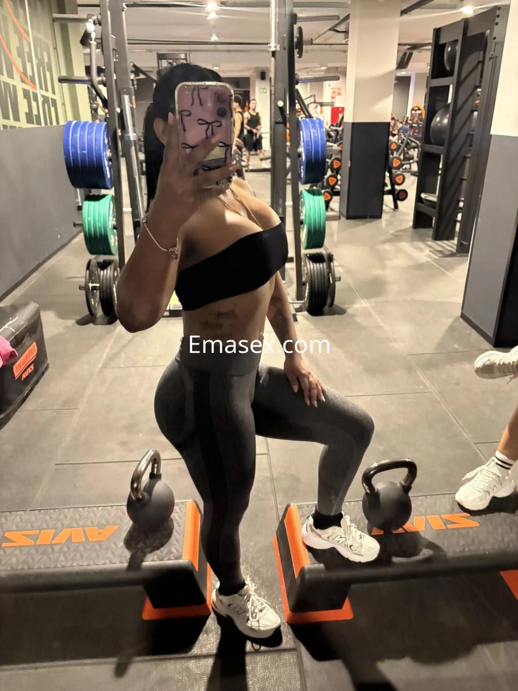 La puta en Albacete luce un top negro y leggings ajustados mientras posa en un gimnasio.