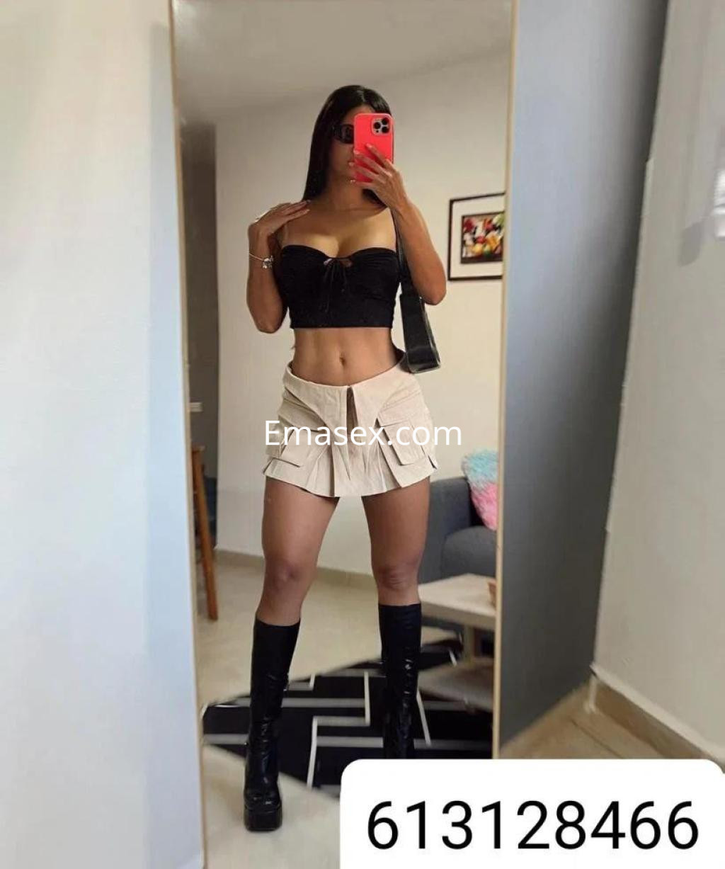 La puta luce un top negro ajustado y una falda corta de pliegues, posando en un interior luminoso en Zamora.