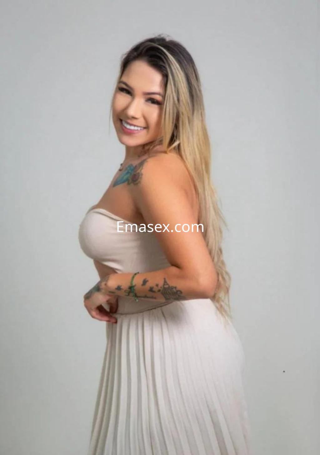Puta de Lugo sonríe mientras posa con un vestido claro y ligero que resalta su figura y tatuajes.