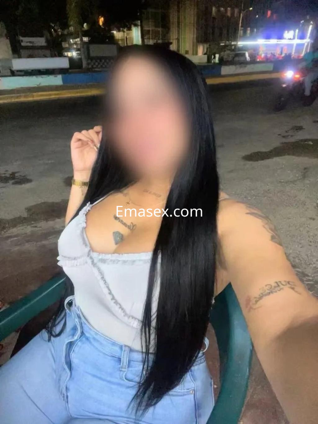 Puta posando en una silla con blusa sin mangas y pantalones ajustados, en un entorno urbano de Valladolid.